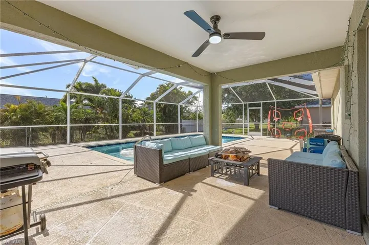 Swimming pool featuring an outdoor living space with a fire pit, a patio area, a grill, and glass enclosure