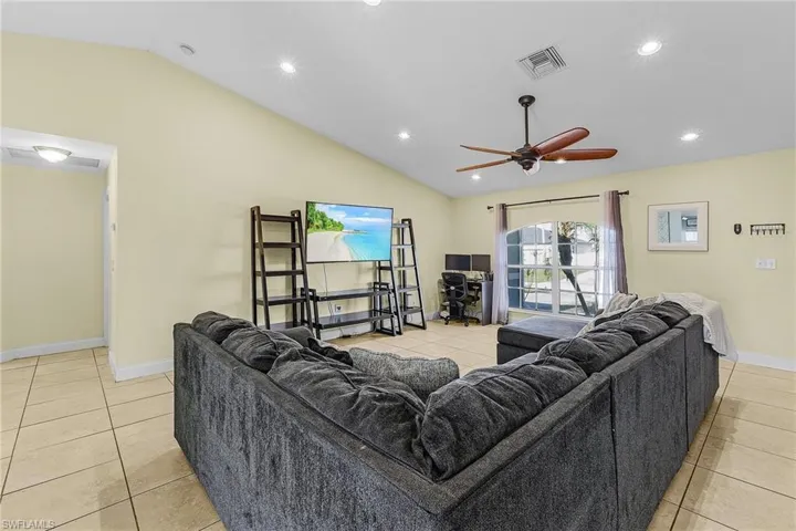 Living room featuring vaulted ceiling, light tile patterned floors, recessed lighting, baseboards, and ceiling fan