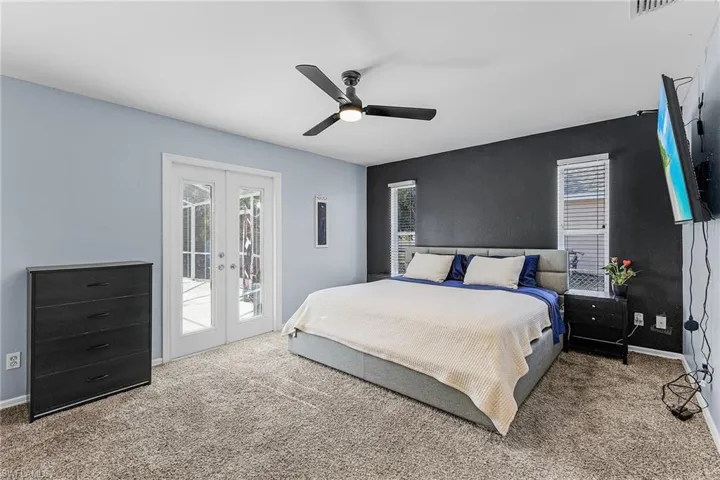 Carpeted bedroom featuring french doors, access to exterior, and multiple windows