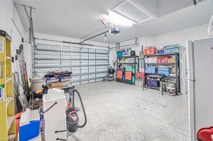 Garage with freestanding refrigerator and a garage door opener