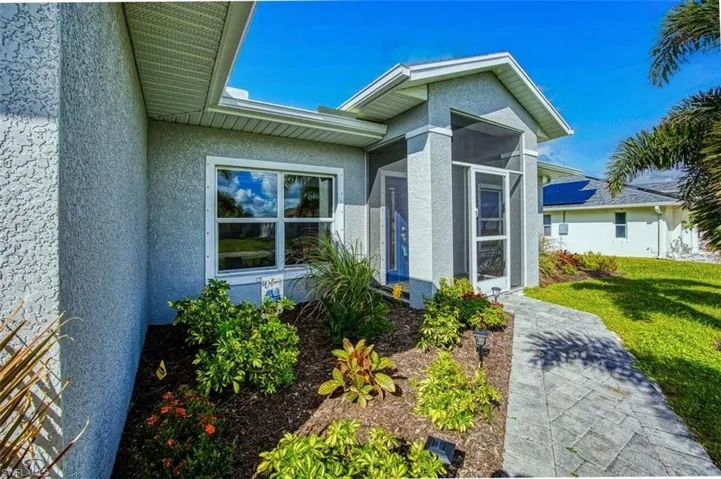 Property entrance with a sunroom, stucco siding, and a yard