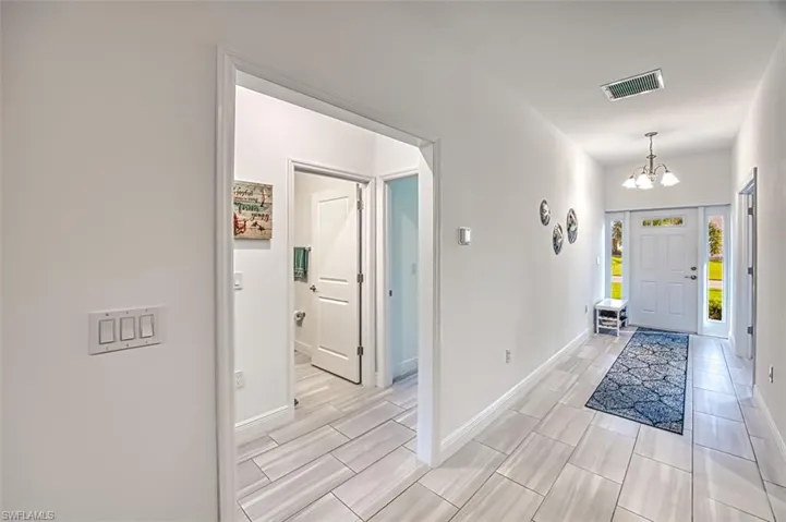 Foyer with baseboards and a chandelier