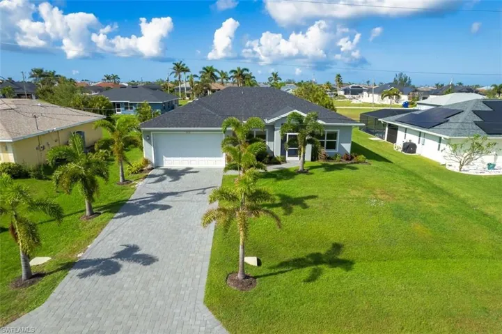 Ranch-style house featuring a residential view, decorative driveway, a front yard, and a garage