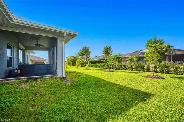 View of green lawn with a ceiling fan and glass enclosure