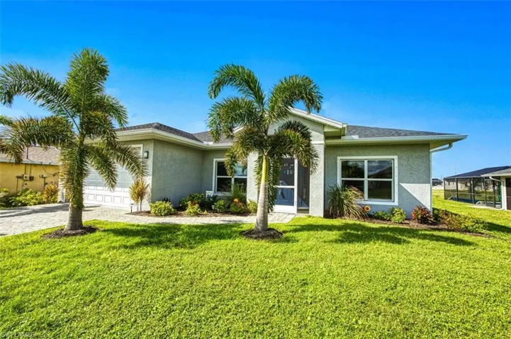 View of front of house with a front lawn, stucco siding, decorative driveway, and an attached garage