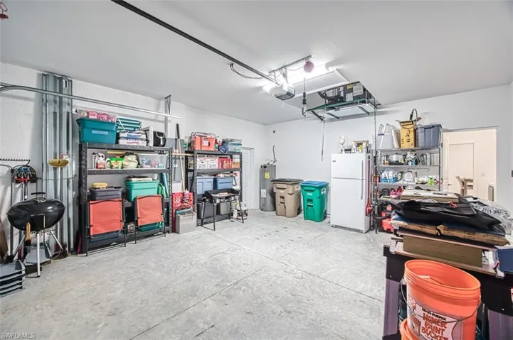 Garage with freestanding refrigerator, water heater, and a garage door opener