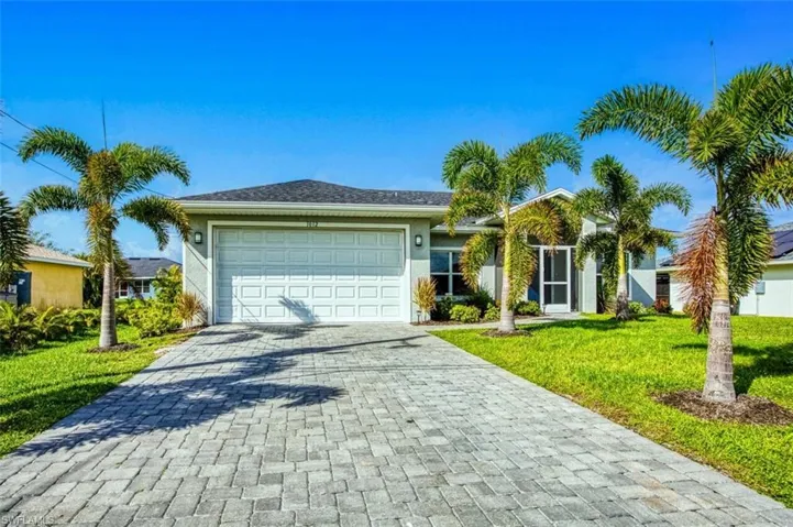Ranch-style home featuring a front lawn, decorative driveway, a garage, and stucco siding