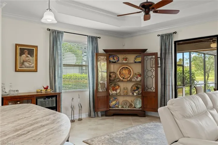 Tiled bedroom with ornamental molding, ceiling fan, and a raised ceiling