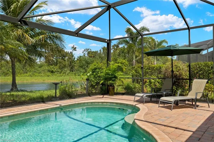 View of swimming pool featuring a patio, a water view, and glass enclosure