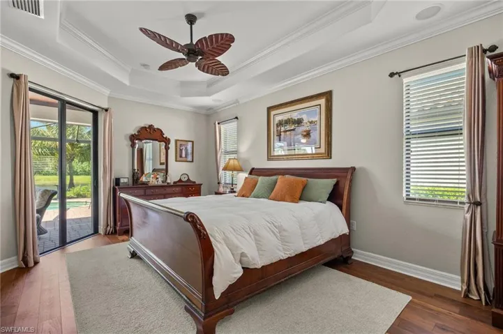 Bedroom with multiple windows, dark hardwood / wood-style floors, access to exterior, and ceiling fan