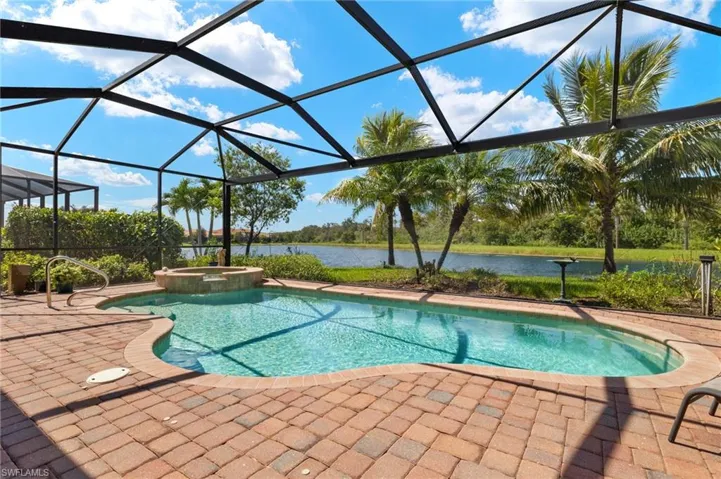 View of swimming pool featuring glass enclosure, a water view, an in ground hot tub, and a patio area