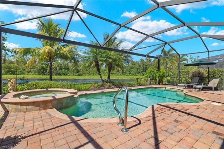 View of pool with a lanai, a water view, an in ground hot tub, and a patio