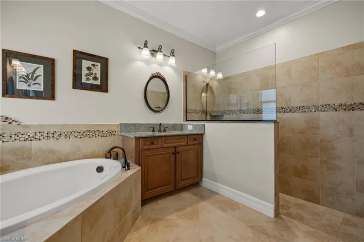 Bathroom with crown molding, vanity, and separate shower and tub