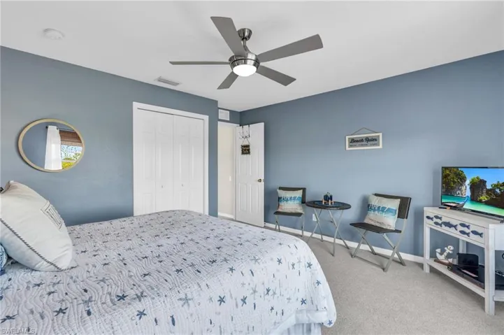 Carpeted bedroom featuring ceiling fan and a closet