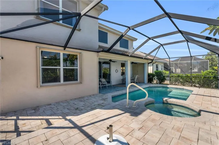 View of swimming pool with glass enclosure, an in ground hot tub, ceiling fan, and a patio area