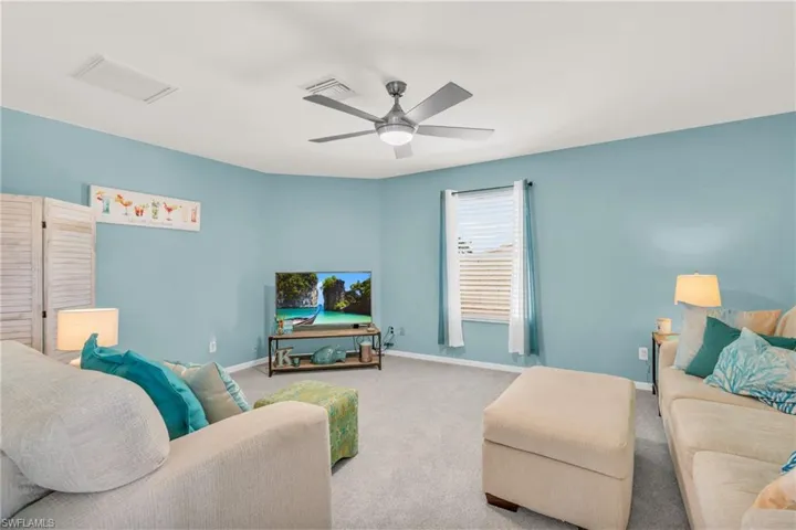 Living room with ceiling fan and light carpet