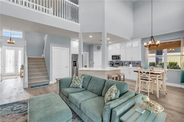 Living room featuring light hardwood / wood-style flooring, a high ceiling, and a healthy amount of sunlight