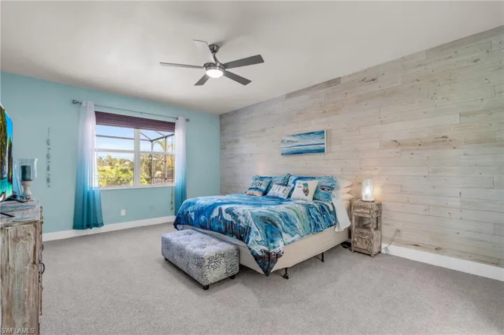 Carpeted bedroom featuring wood walls and ceiling fan