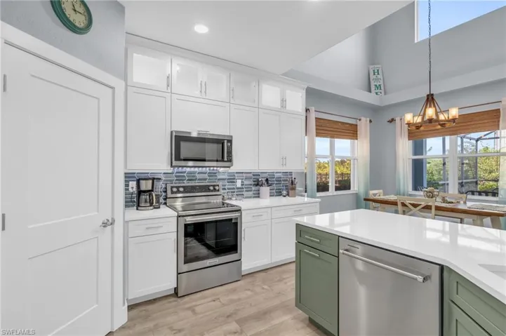 Kitchen featuring white cabinets, green cabinetry, appliances with stainless steel finishes, and light hardwood / wood-style flooring