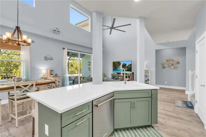 Kitchen with ceiling fan with notable chandelier, hanging light fixtures, light hardwood / wood-style flooring, a towering ceiling, and green cabinets