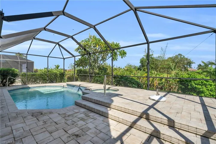 View of pool with a patio, glass enclosure, and an in ground hot tub