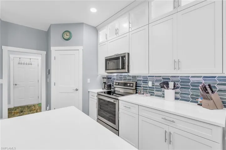 Kitchen with backsplash, stainless steel appliances, and white cabinets