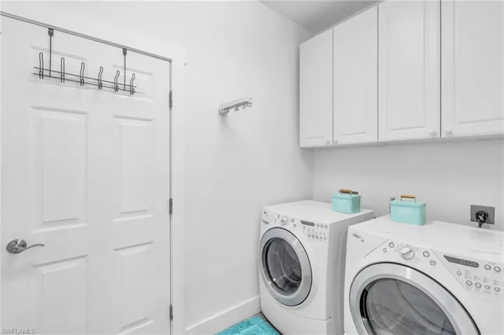 Washroom featuring cabinets and washing machine and clothes dryer