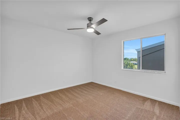 Carpeted empty room featuring ceiling fan