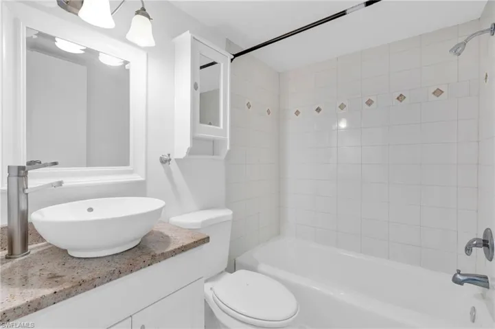 Full bathroom featuring toilet, vanity, and tiled shower / bath