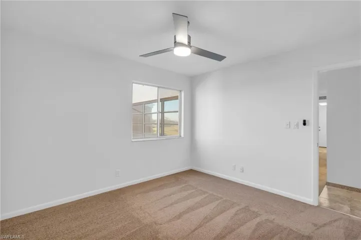 Carpeted spare room featuring ceiling fan