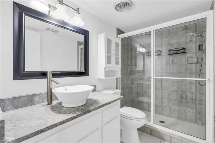 Bathroom with walk in shower, tile patterned floors, vanity, and toilet