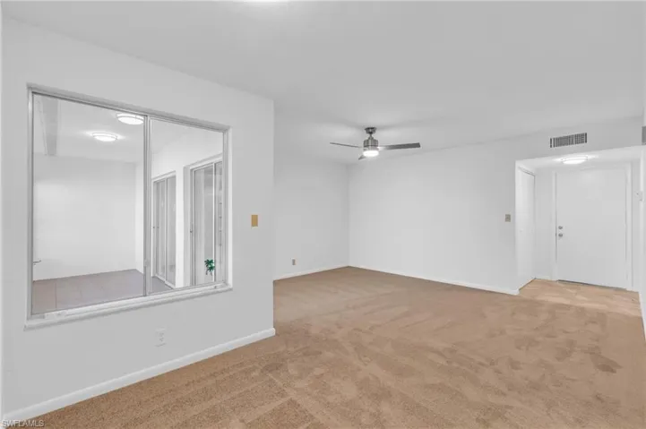 Carpeted living/dining room with ceiling fan