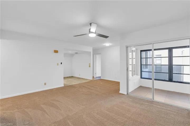 Carpeted living/dining room featuring ceiling fan