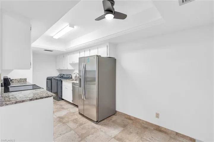 Kitchen featuring a tray ceiling, white cabinetry, ceiling fan, and appliances with stainless steel finishes