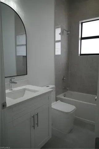 Bathroom with bathtub / shower combination, vanity, plenty of natural light, and light tile patterned floors