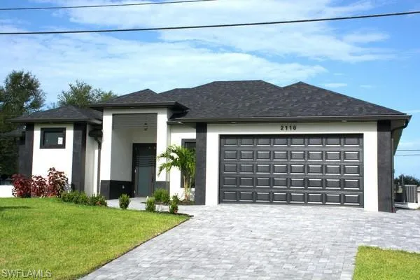 Prairie-style home featuring a garage, central AC, and a front yard