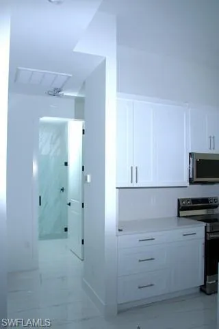 Kitchen featuring appliances with stainless steel finishes and white cabinets