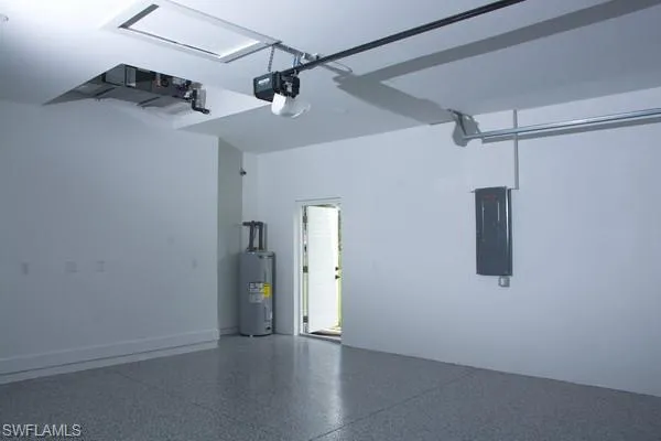 Garage featuring water heater, a garage door opener, and electric panel