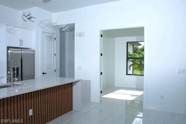 Kitchen featuring white cabinetry, sink, and stainless steel fridge with ice dispenser