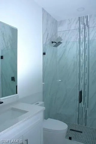 Bathroom with vanity, an enclosed shower, and toilet