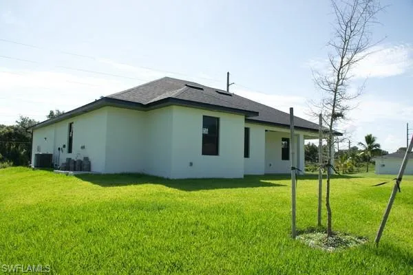 Rear view of property with a yard and central AC unit