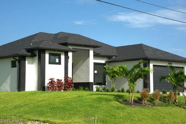 View of front of property featuring a garage and a front lawn
