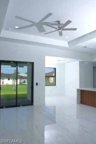 Spare room with ceiling fan and a tray ceiling
