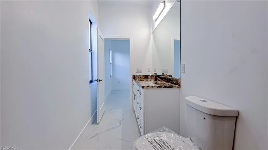 Bathroom with vanity, light marble finish flooring, and healthy amount of natural light