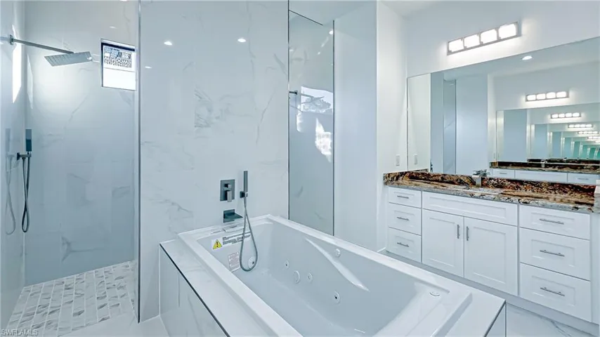 Bathroom with a marble finish shower, a tub with jets, and vanity