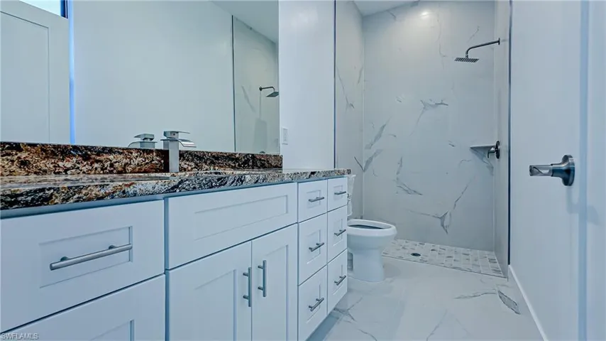 Full bath with vanity, a marble finish shower, and light marble finish floors