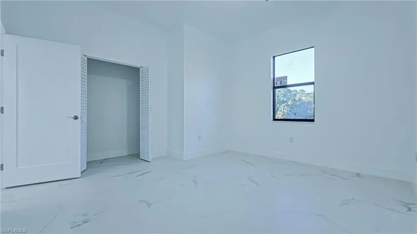 Unfurnished bedroom with a closet and light marble finish flooring