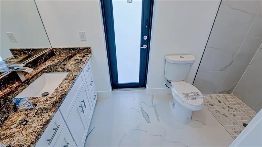 Bathroom featuring vanity, light marble finish floors, and a shower stall