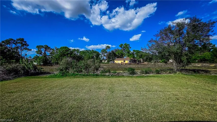 View of green lawn featuring view of wooded area
