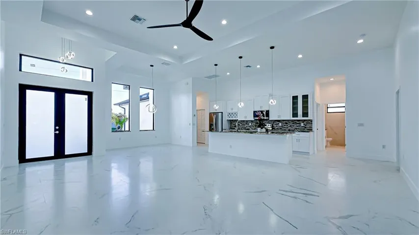 Living room featuring a high ceiling, ceiling fan, recessed lighting, french doors, and light marble finish flooring